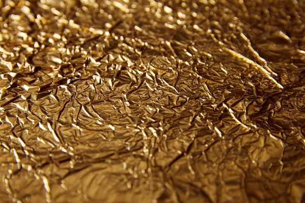Selective focus of sheet golden foil with glares — Stock Photo