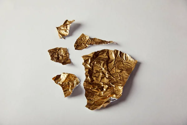 Top view of pieces golden foil on white background — Stock Photo