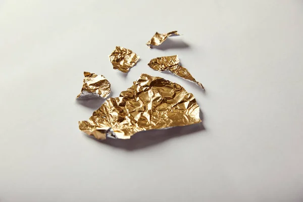 Pieces of golden foil on white background — Stock Photo