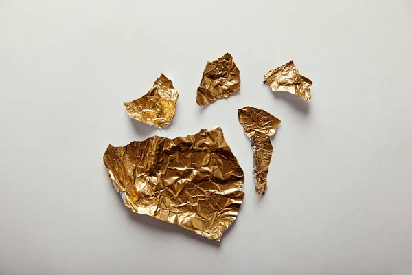 Top view of pieces golden foil with glares on white background — Stock Photo