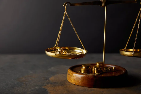 Golden stones on scales on marble surface and black background — Stock Photo