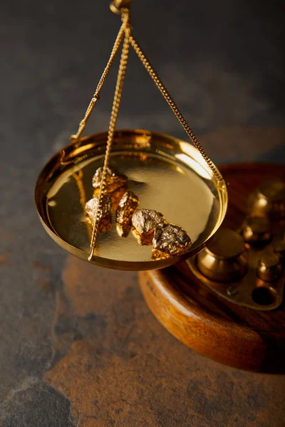 Golden stones on scales on marble table — Stock Photo