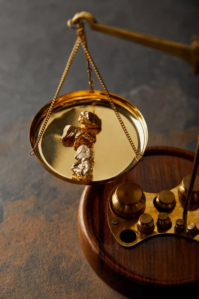 Golden stones on  wooden scales on marble table — Stock Photo