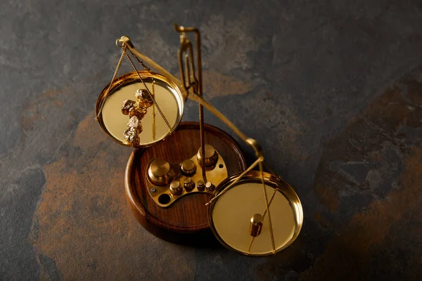 Golden stones on scales on grey and brown marble table — Stock Photo