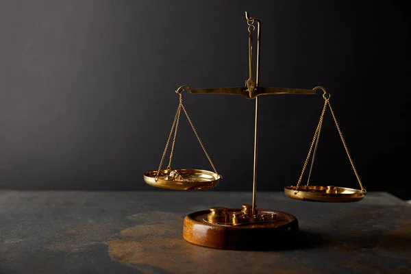 Golden stones on scales on marble table and dark background — Stock Photo