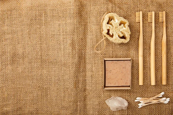 Top view of different hygiene and care items on brown sackcloth surface, zero waste concept — Stock Photo