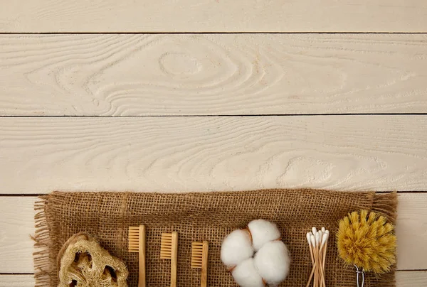 Top view of hygiene and care items arranged on sackcloth on white wooden surface, zero waste concept — Stock Photo