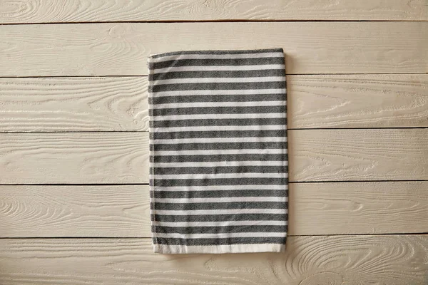 Top view of striped grey and white towel on white wooden surface — Stock Photo
