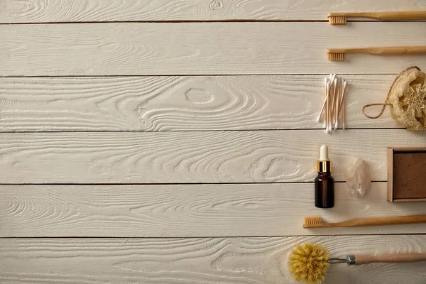 Vue de dessus de divers articles d'hygiène et d'entretien disposés sur une surface en bois blanc, concept zéro déchet — Photo de stock