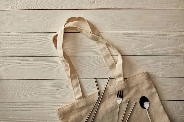 Vue du dessus des articles de coutellerie et sac en coton sur une surface en bois blanc, concept zéro déchet — Photo de stock