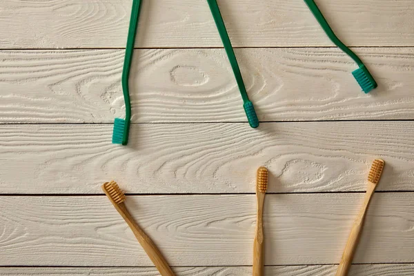 Vista superior de diferentes escovas de dentes na superfície de madeira branca, conceito de desperdício zero — Fotografia de Stock