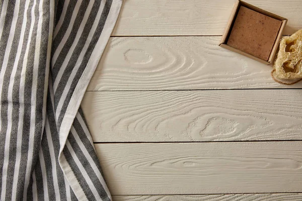 Vista superior de los artículos de cuidado e higiene y toalla rayada en la superficie de madera blanca, concepto de cero residuos - foto de stock