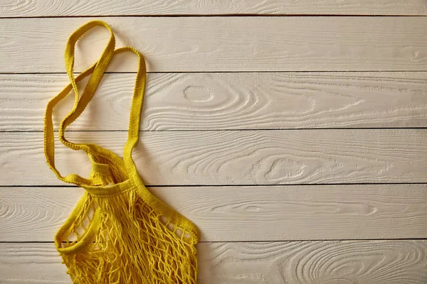 Vista superior de la bolsa de hilo amarillo vacío en la superficie de madera blanca, concepto de cero residuos - foto de stock