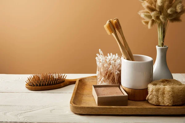 Wooden tray with different hygiene and care items, and hair brush on white wooden surface, zero waste concept — Stock Photo