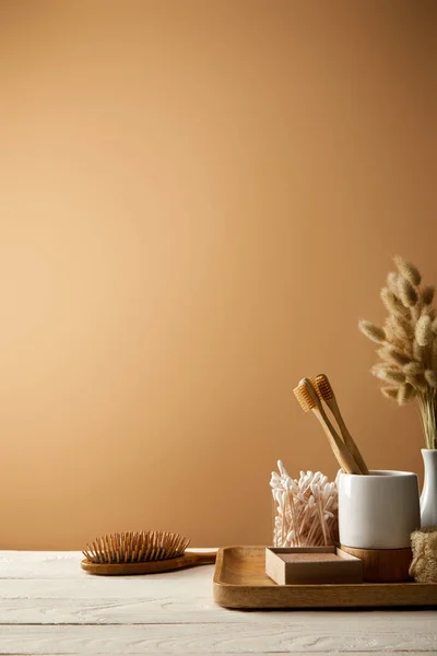 Bandeja de madera con diferentes artículos de higiene y cuidado, y cepillo aislado en marrón, cero concepto de residuos - foto de stock