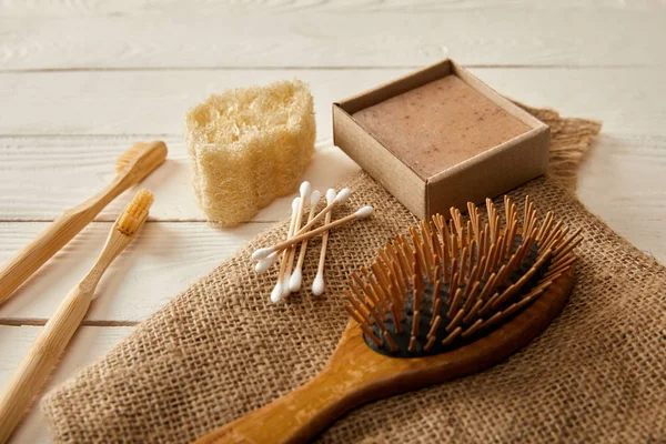 Different hygiene and care items on sackcloth on white wooden surface, zero waste concept — Stock Photo