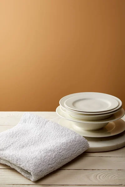 Stack of plates and terry cotton towel on white wooden surface — Stock Photo