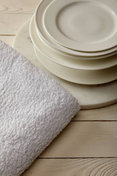 Stacked plates and white terry cotton towel on white wooden surface — Stock Photo