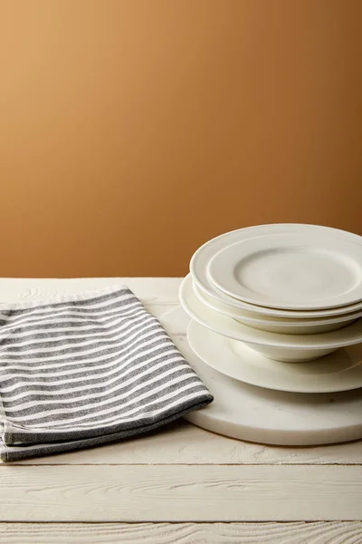 Serviette en coton rayé et pile de assiettes sur une surface en bois blanc — Photo de stock