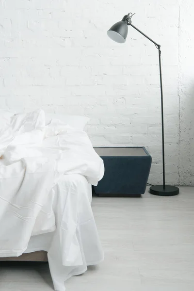 Bed with white sheets and blanket, lamp and black nightstand — Stock Photo