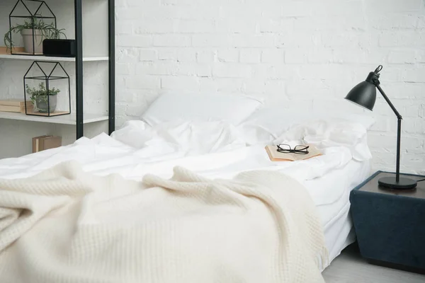 Chambre avec étagère, lit blanc et lampe sur table de chevet — Photo de stock