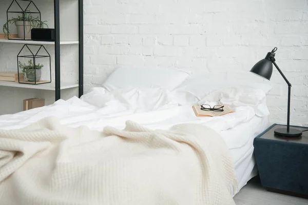 Quarto com cremalheira, cama branca e lâmpada na mesa de cabeceira — Fotografia de Stock