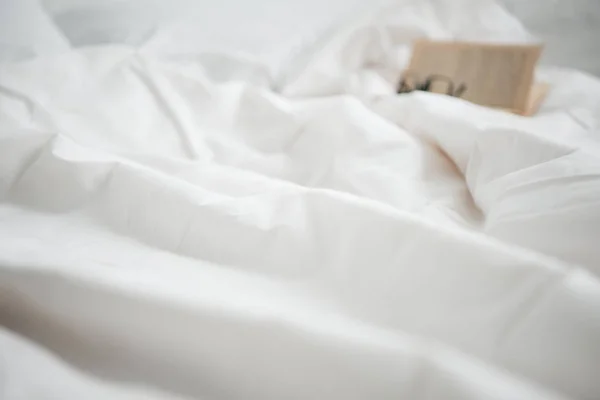 Enfoque selectivo de libro y vasos en la cama vacía blanca - foto de stock