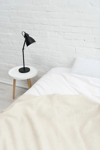 Gemütliches Schlafzimmer mit Kissen auf dem Bett und Lampe auf dem Hocker — Stockfoto