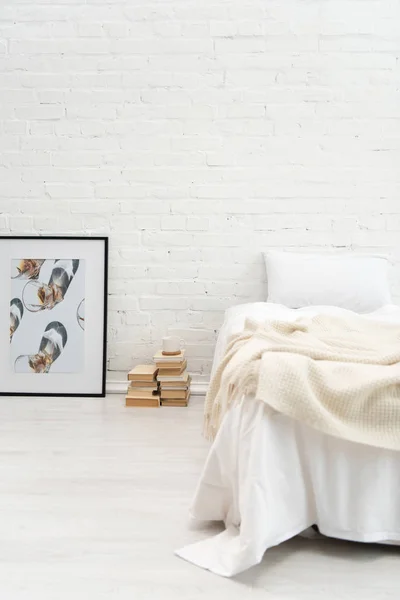 Спальня з подушкою на порожньому ліжку і книгах, картина на підлозі — стокове фото