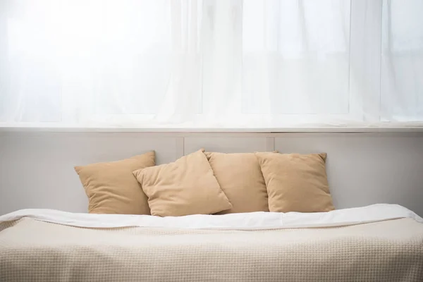 Acogedora cama con almohadas marrones y manta blanca - foto de stock