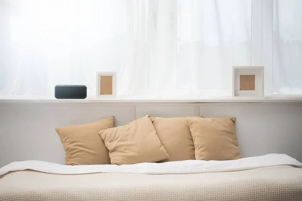 Dormitorio con almohadas marrones en la cama, despertador y marcos de fotos - foto de stock