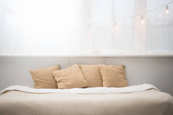 Dormitorio con almohadas marrones y manta blanca en la cama - foto de stock