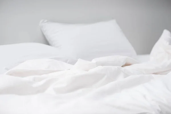 Enfoque selectivo de la cama acogedora vacía con almohadas blancas y manta - foto de stock