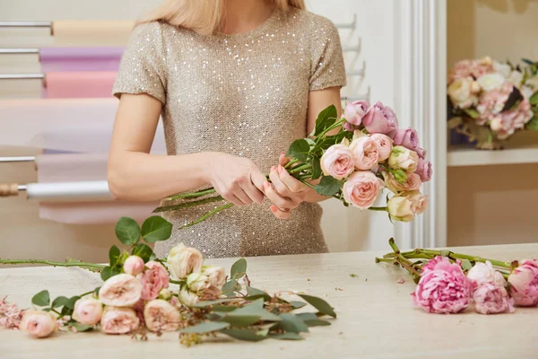 Cropped view of florist making bouquet of roses and peonies — Stock Photo