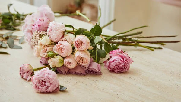 Ramo con rosas y peonías en la mesa en la florería — Stock Photo