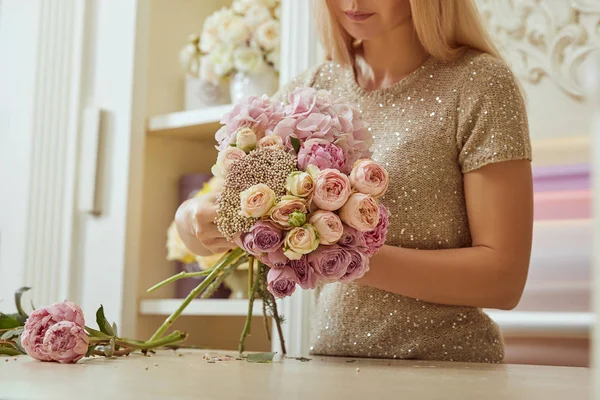 Foco seletivo de visão parcial de florista fazendo buquê de rosas e peônias no espaço de trabalho — Fotografia de Stock