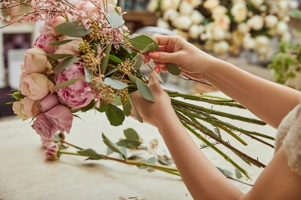 Florist macht Blumenstrauß aus Rosen und Pfingstrosen am Arbeitsplatz — Stockfoto