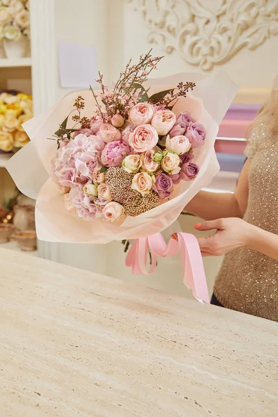Partial view of florist holding bouquet of roses and peonies — Stock Photo
