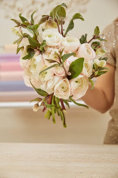 Cropped view of florist holding bouquet of white peonies at workspace — Stock Photo