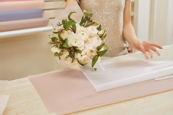 Partial view of florist wrapping bouquet of white peonies at workspace — Stock Photo