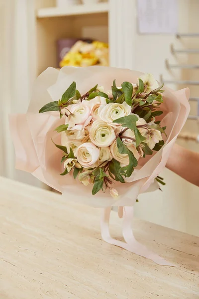 Vue partielle du fleuriste tenant un bouquet de pivoines blanches sur le lieu de travail — Photo de stock