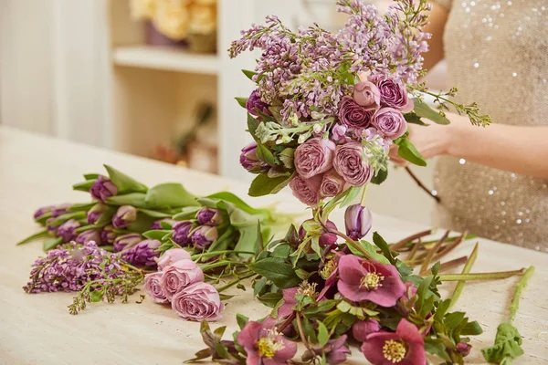 Selective focus of florist making bouquet of tulips, peonies and lilac — Stock Photo