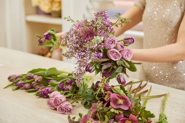 Vue partielle du fleuriste faisant bouquet de tulipes, pivoines et lilas sur le lieu de travail — Photo de stock