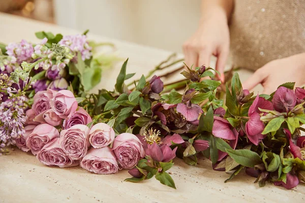 Partial view of florist making bouquet of tulips, peonies and lilac at workspace — Stock Photo