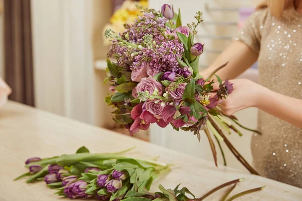 Vista cortada de florista fazendo buquê de tulipas, peônias e lilás no espaço de trabalho — Fotografia de Stock