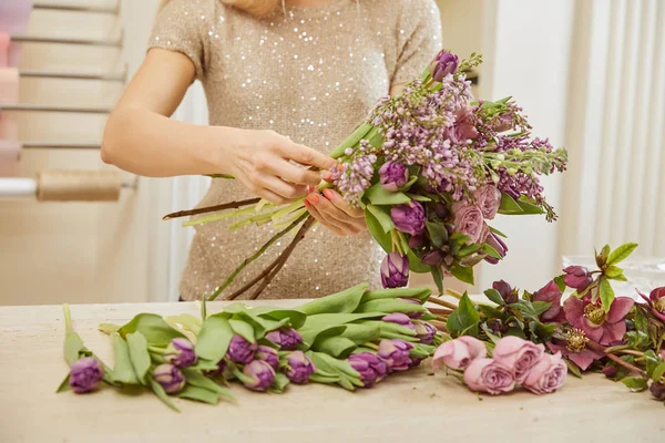 Partial view of florist making bouquet of tulips, peonies and lilac at flower shop — Stock Photo