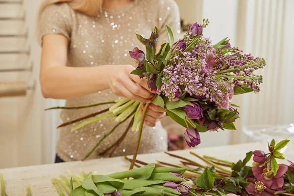 Floristin macht Strauß aus Tulpen, Pfingstrosen und Flieder am Arbeitsplatz — Stockfoto