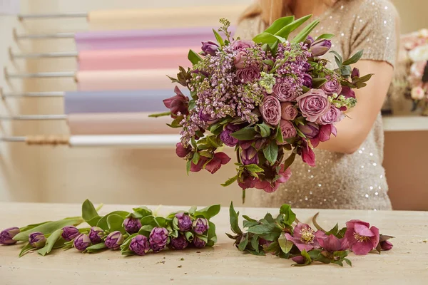 Vista recortada de floristería haciendo ramo de tulipanes púrpura, peonías y lila en la tienda de flores - foto de stock