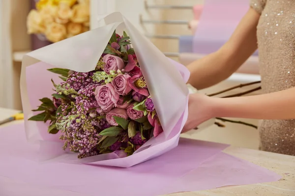 Vista ritagliata di fiorista che fa mazzo di tulipani, peonie e lilla sul tavolo — Foto stock