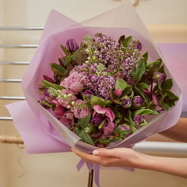 Vue recadrée du fleuriste tenant un bouquet de tulipes, pivoines et lilas — Photo de stock